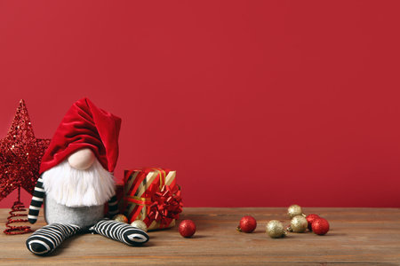 Christmas gnome with gift boxes and decorations on red backgroundの写真素材