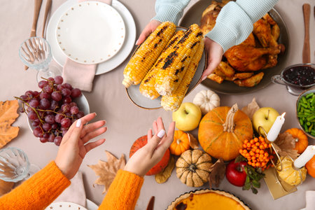 Women with tasty food on dining table set for Thanksgiving Day, top viewの写真素材