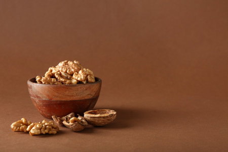 Bowl of tasty walnuts on brown backgroundの写真素材