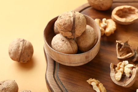 Bowl of tasty walnuts on yellow backgroundの写真素材