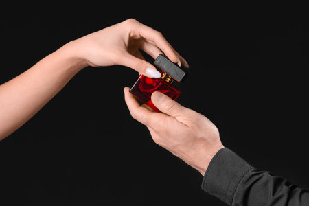 Young couple with perfume on dark background, closeupの写真素材