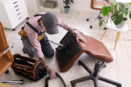 Male worker assembling chair in officeの写真素材