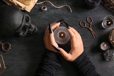 Witch with burning candle on dark tableの写真素材