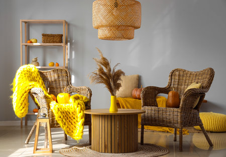 Autumn interior of living room with wicker armchairs, pumpkins and pampas grass on coffee tableの写真素材