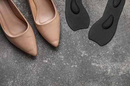 Pair of black orthopedic insoles and high heeled shoes on grunge backgroundの写真素材