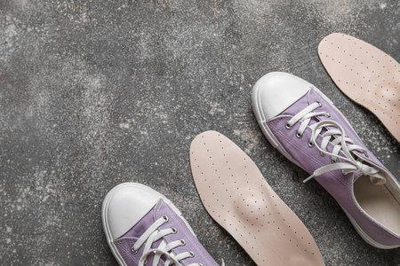 Pair of stylish gumshoes and orthopedic insoles on grunge backgroundの写真素材