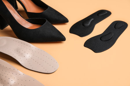Stylish high heeled shoes and orthopedic insoles on color background, closeupの写真素材