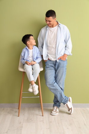 Young man with his little son near green wallの写真素材