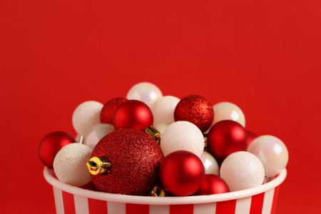 Popcorn bucket with beautiful Christmas balls on red background, closeupの写真素材