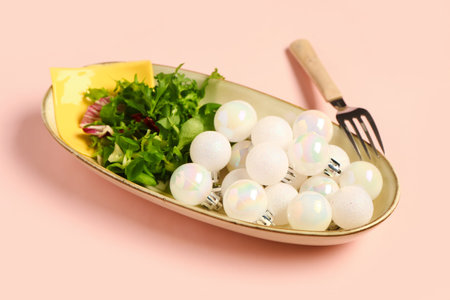 Plate with beautiful Christmas balls and salad on color background