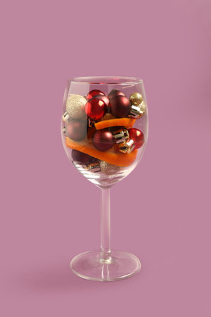 Glass with beautiful Christmas balls and orange slices on color backgroundの写真素材