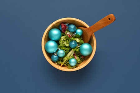 Wooden bowl of salad with Christmas balls on color backgroundの写真素材
