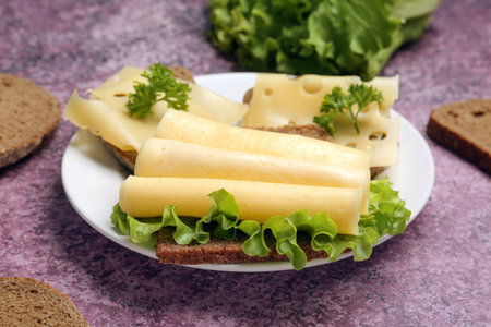 Tasty sandwiches with cheese and lettuce in plate on pink background, closeupの写真素材