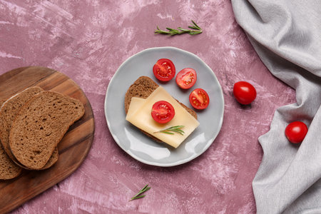 Tasty sandwich with cheese and tomatoes in plate on pink backgroundの写真素材