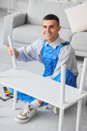 Male worker assembling furniture in roomの写真素材