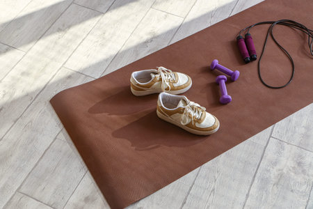 Fitness mat with sneakers, dumbbells and skipping rope on floorの写真素材