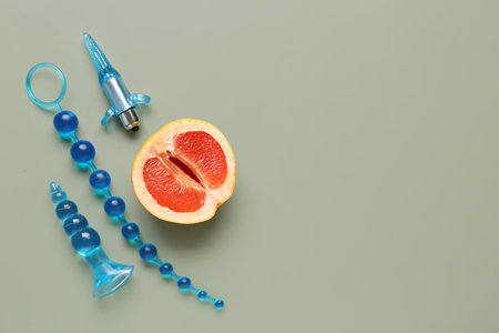 Anal plugs from sex shop and half of tasty grapefruit on green backgroundの写真素材