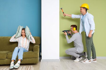Young woman suffering from loud neighbors renovating at homeの写真素材