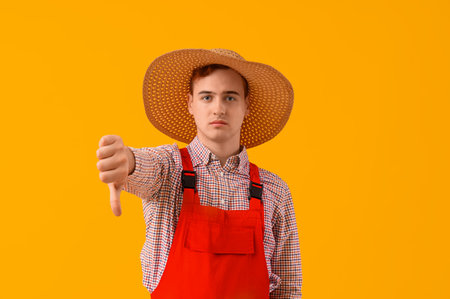 Young farmer showing dislike on yellow backgroundの写真素材