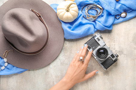 Female hand with photo camera, accessories and pumpkin on grunge backgroundの写真素材