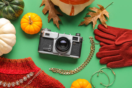 Composition with vintage photo camera, female accessories and pumpkins on green backgroundの写真素材