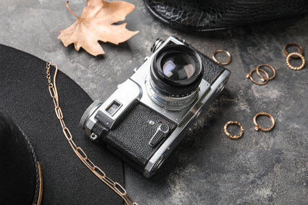 Composition with vintage photo camera and stylish female accessories on grunge background