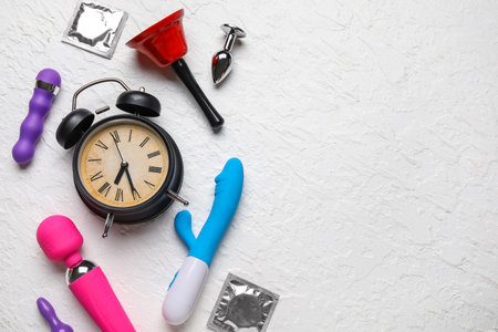 Alarm clock with different toys and condom on grunge white background. Time for sexの写真素材
