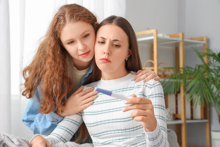 Upset young lesbian couple with pregnancy test at homeの写真素材
