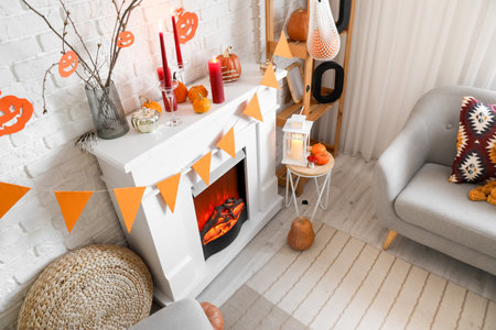 White fireplace with Halloween decorations and garland in festive living roomの写真素材