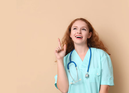 Female doctor pointing at something on beige backgroundの写真素材