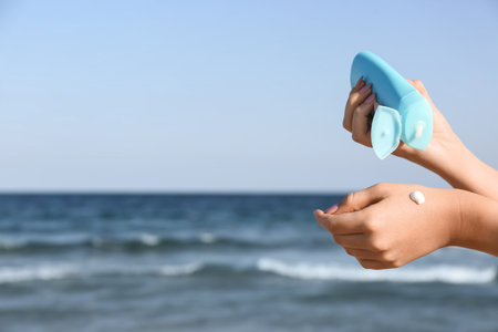 Young woman applying sunscreen cream on body at resort