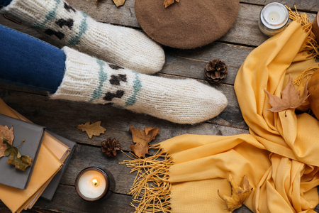 Female legs in warm socks, accessories and fallen leaves on wooden background, closeupの写真素材