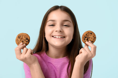 Happy girl holding sweet chocolate cookies on blue background