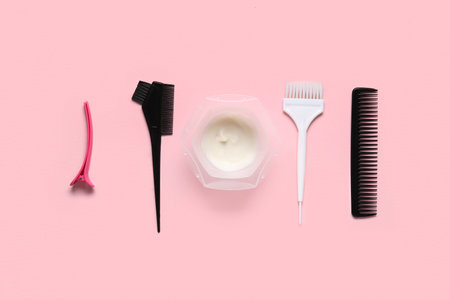 Bowl with hair dye, combs and brushes on pink backgroundの写真素材