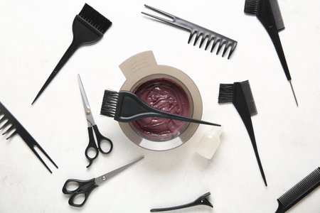 Bowl with hair dye and set of hairdresser's tools on white backgroundの写真素材