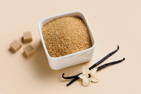 Bowl with aromatic vanilla sugar, flower and sticks on beige backgroundの写真素材