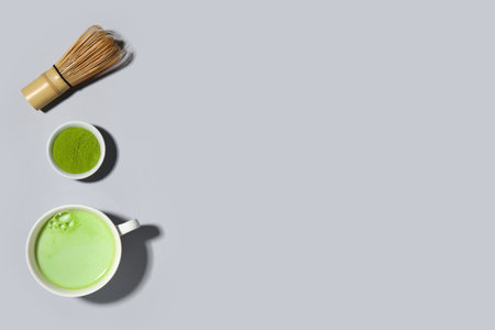 Cup of fresh matcha tea, powder and chasen on gray backgroundの写真素材