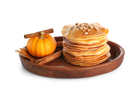Plate of tasty pumpkin pancakes with honey, nuts and cinnamon on white backgroundの写真素材