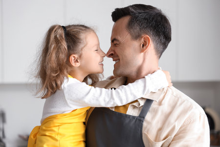 Cute little girl with her dad hugging in kitchen, closeupの写真素材