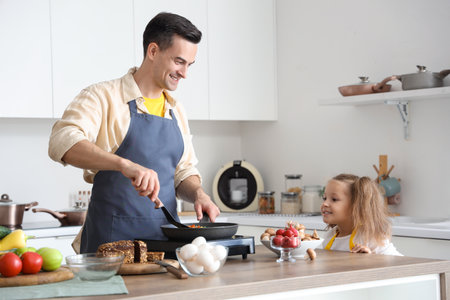 Cute little girl with her dad cooking in kitchenの写真素材