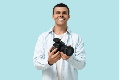 Male photographer with modern camera on blue backgroundの写真素材