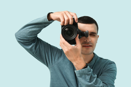 Male photographer with modern camera on light backgroundの写真素材