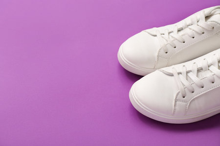 Stylish white sneakers on purple backgroundの写真素材