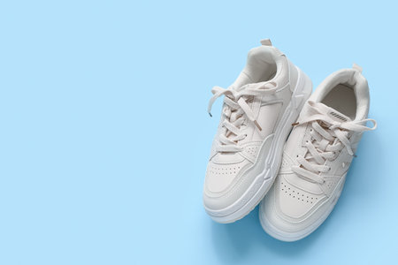 Stylish white sneakers on blue backgroundの写真素材
