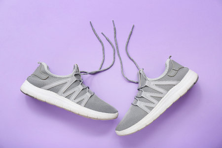 Stylish gray sneakers on purple background