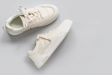 Stylish white sneakers on gray background