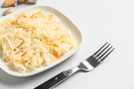 Plate with tasty sauerkraut and ingredients on white backgroundの写真素材