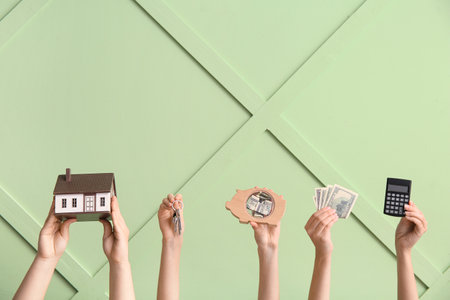 Female hands with house figure, keys, money and calculator against color wall. Concept of buying real estateの写真素材