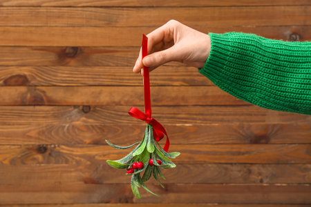 Female hand with mistletoe branch on wooden backgroundの写真素材