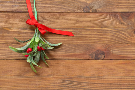Mistletoe branch with ribbon on wooden backgroundの写真素材